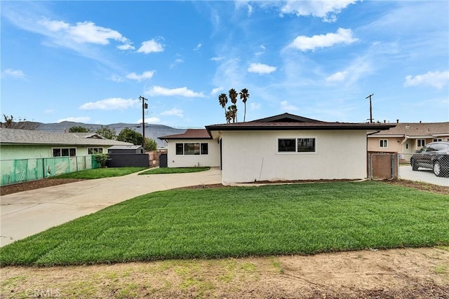 view of side of home featuring fence, a lawn, and stucco siding