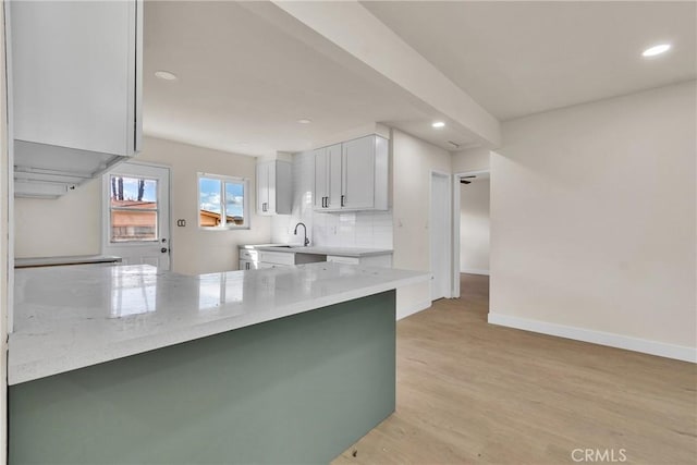 kitchen featuring recessed lighting, a peninsula, baseboards, light wood-style floors, and tasteful backsplash