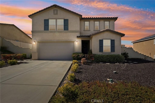 view of front of property with concrete driveway, a tiled roof, an attached garage, and stucco siding