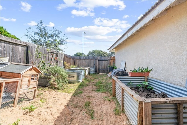 view of yard featuring a garden, an outdoor structure, and a fenced backyard