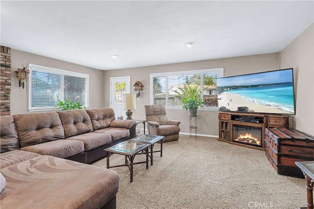 living area with carpet floors, a glass covered fireplace, and baseboards