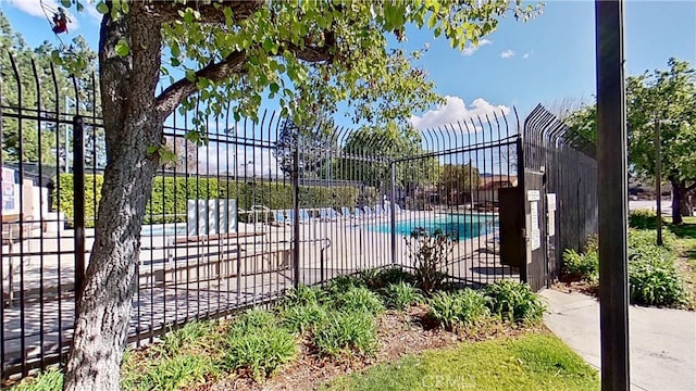 view of gate with fence and a community pool