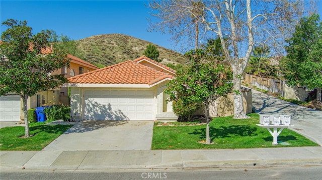 view of front of home featuring an attached garage, a mountain view, driveway, a tiled roof, and a front lawn