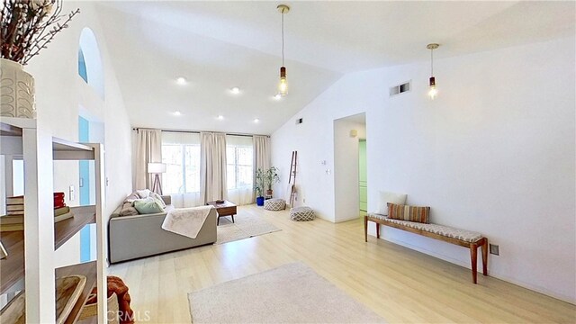 living area with high vaulted ceiling, visible vents, and wood finished floors