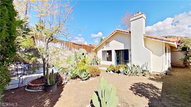 back of house featuring fence, a tile roof, stucco siding, a chimney, and a patio area