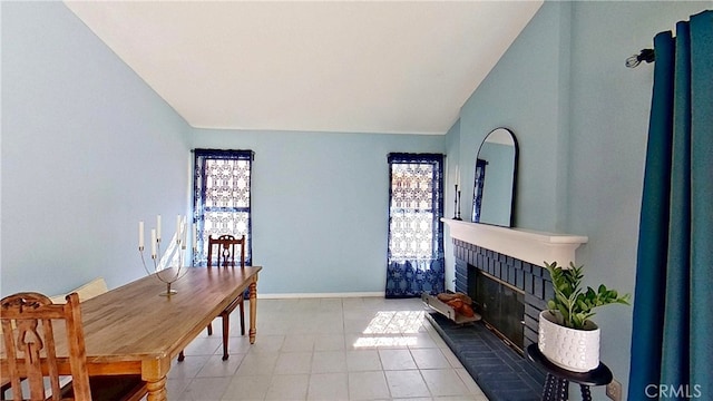 dining area featuring a brick fireplace, vaulted ceiling, and baseboards