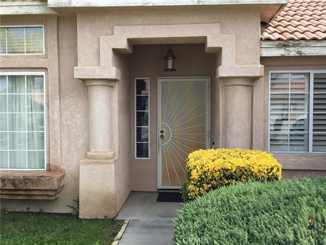 doorway to property with a tile roof and stucco siding