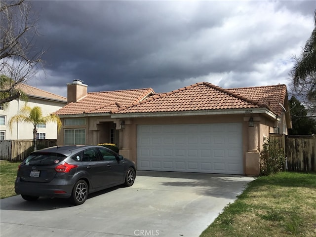 view of front of property featuring a garage, driveway, fence, and stucco siding