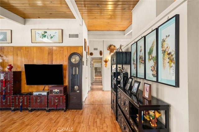 living room featuring visible vents, wooden walls, wood finished floors, wooden ceiling, and beamed ceiling