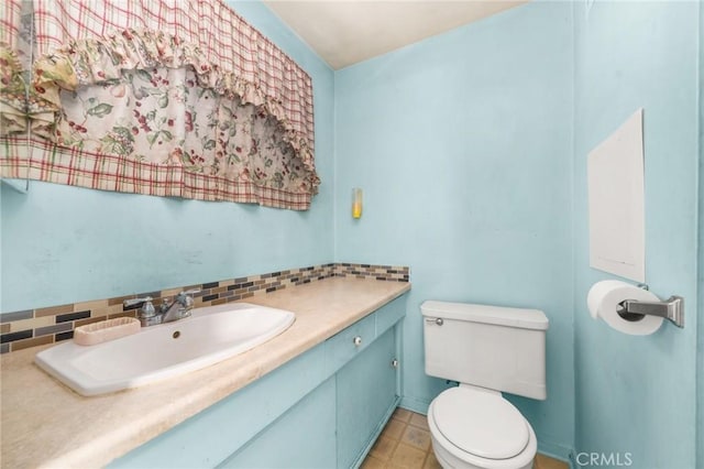 half bathroom featuring tasteful backsplash, vanity, and toilet