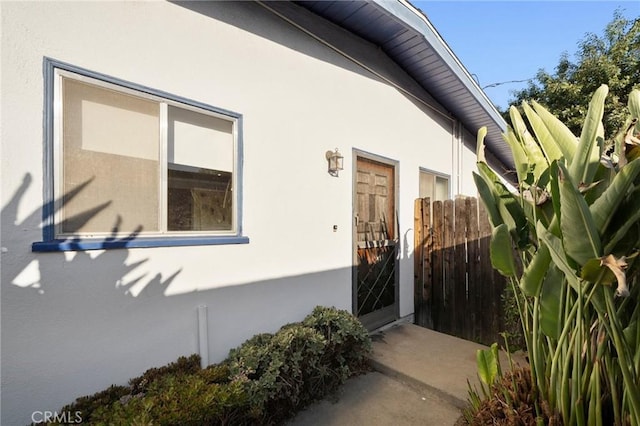 view of exterior entry featuring fence and stucco siding