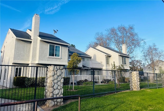 back of property featuring fence, a lawn, a chimney, and stucco siding