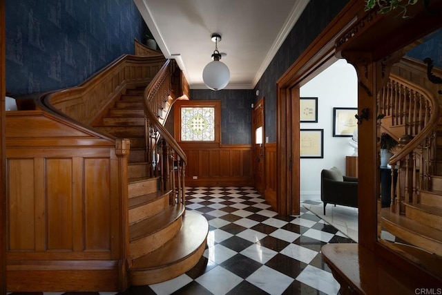 entrance foyer featuring a wainscoted wall, ornamental molding, stairway, and tile patterned floors