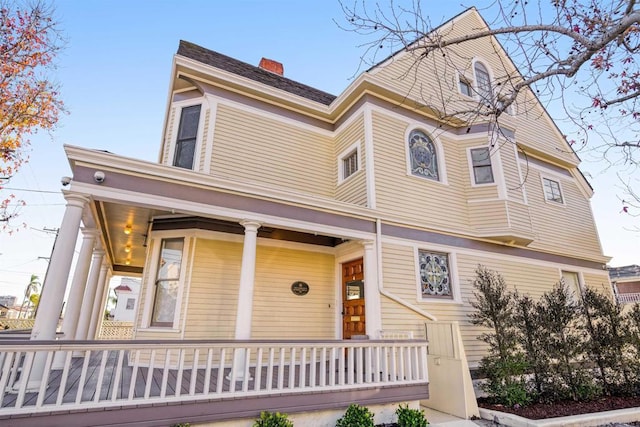 victorian-style house with covered porch and a chimney