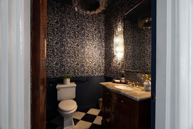 bathroom with a wainscoted wall, vanity, and toilet