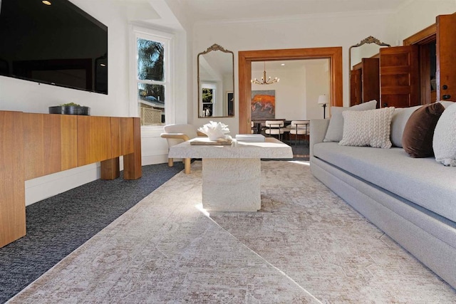 carpeted living area with baseboards, an inviting chandelier, and crown molding