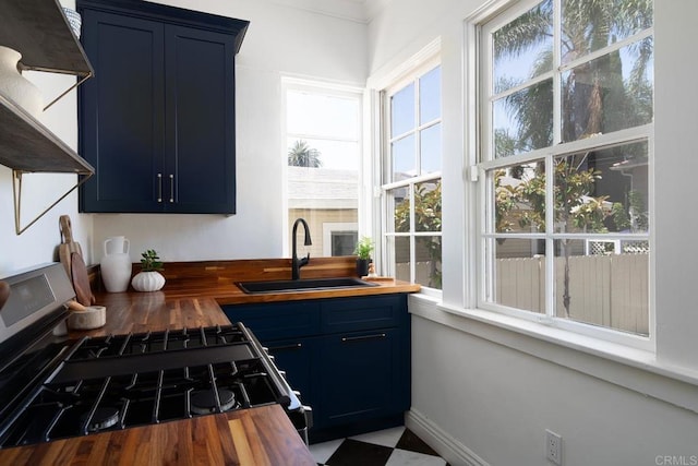 kitchen featuring a sink, gas stove, wood counters, and blue cabinets