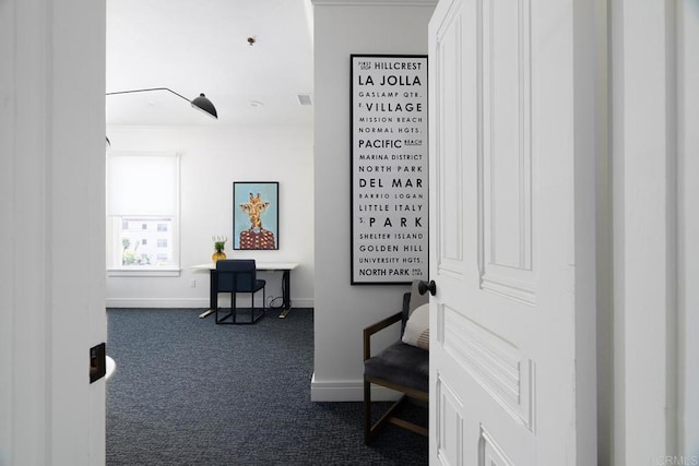 hall featuring crown molding, dark carpet, and baseboards