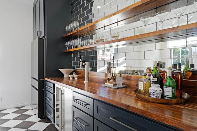 bar featuring decorative backsplash, dark floors, a bar, and wine cooler