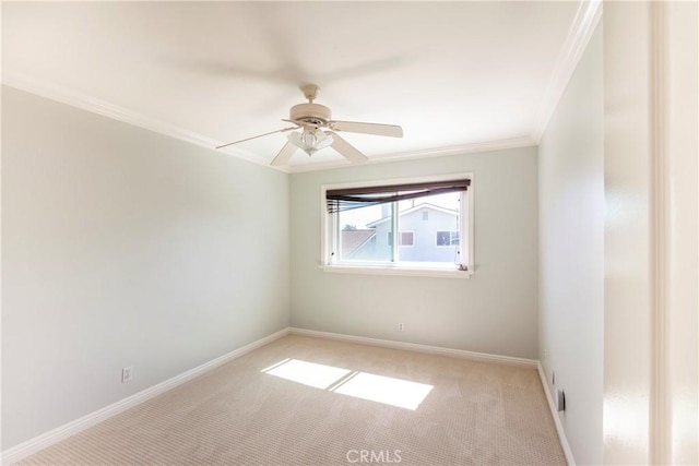 spare room with light carpet, a ceiling fan, baseboards, and crown molding