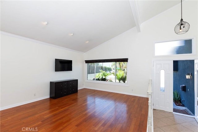 unfurnished living room with ornamental molding, wood finished floors, high vaulted ceiling, beamed ceiling, and baseboards