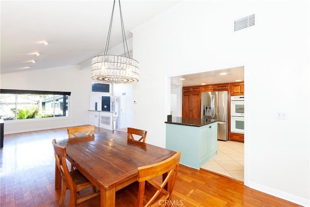 dining area featuring a notable chandelier, visible vents, light wood-style floors, high vaulted ceiling, and baseboards