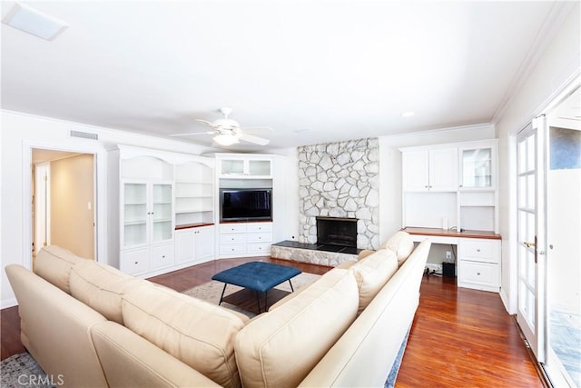 living area featuring ceiling fan, dark wood-style flooring, visible vents, ornamental molding, and built in desk