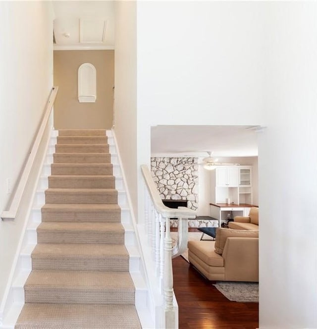 staircase featuring ornamental molding, wood finished floors, a ceiling fan, and baseboards