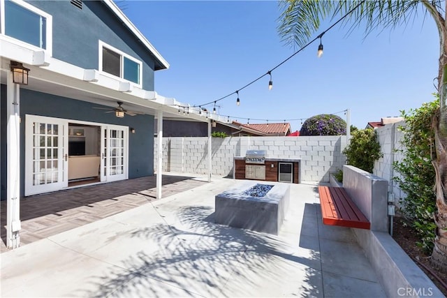 view of patio with ceiling fan, french doors, an outdoor kitchen, and a fenced backyard