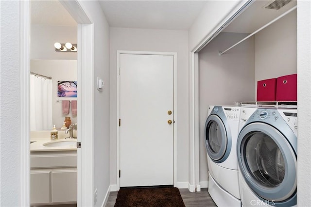 clothes washing area with dark wood-type flooring, a sink, visible vents, and washer and dryer