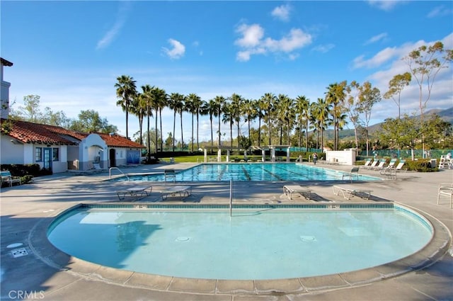 community pool with a patio and fence