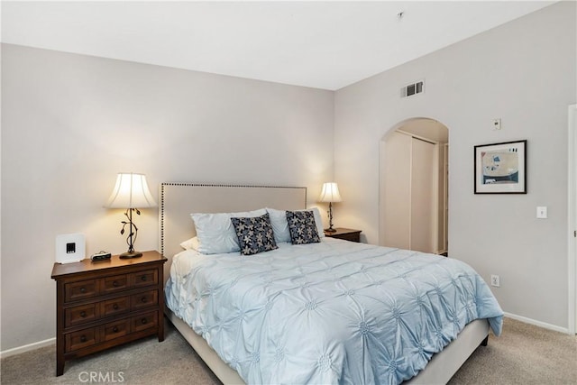 bedroom featuring arched walkways, carpet floors, visible vents, baseboards, and a closet