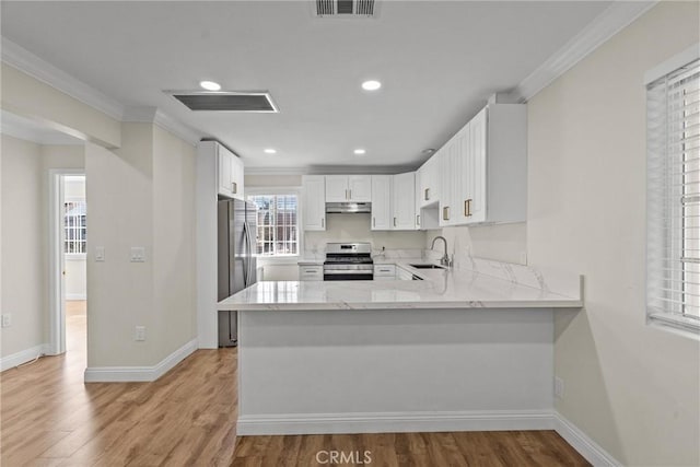 kitchen with visible vents, light stone counters, a peninsula, stainless steel appliances, and a sink