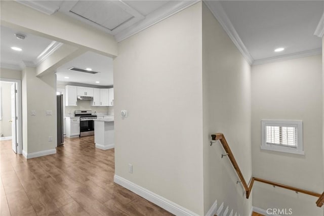 hall featuring an upstairs landing, crown molding, baseboards, and wood finished floors