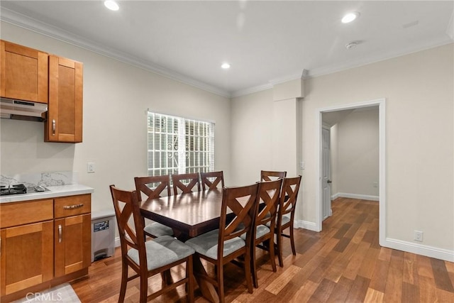 dining area with wood finished floors, baseboards, and ornamental molding