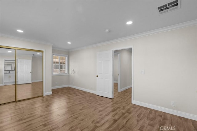 unfurnished bedroom with visible vents, baseboards, wood finished floors, and crown molding