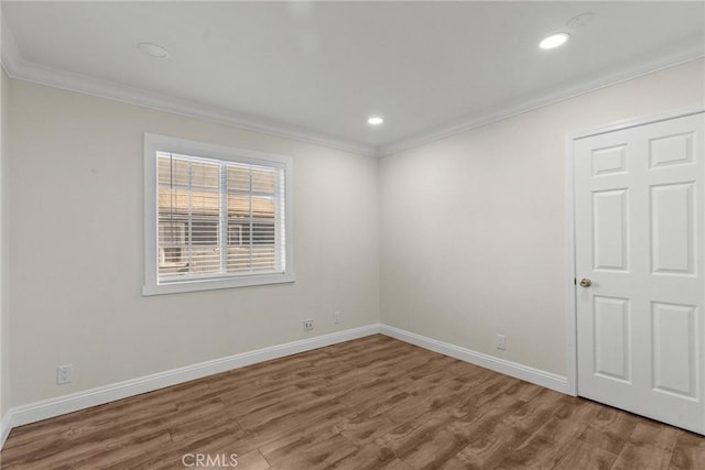 empty room with crown molding, baseboards, and wood finished floors