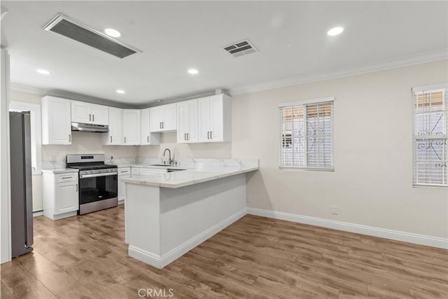 kitchen featuring under cabinet range hood, visible vents, appliances with stainless steel finishes, and a peninsula