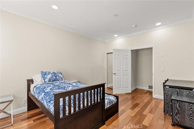 bedroom featuring visible vents, baseboards, light wood-style flooring, and ornamental molding