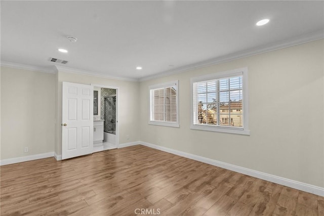 spare room with visible vents, baseboards, wood finished floors, and crown molding