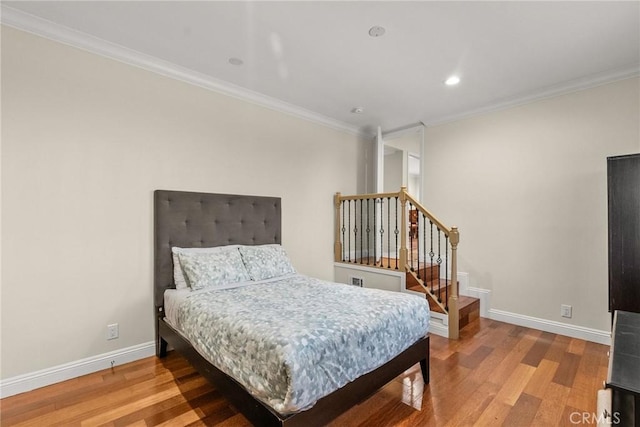 bedroom featuring recessed lighting, baseboards, wood finished floors, and crown molding