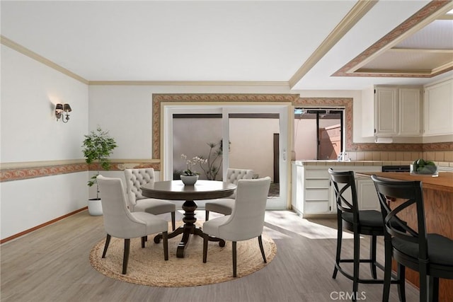 dining room featuring ornamental molding, light wood-type flooring, and baseboards