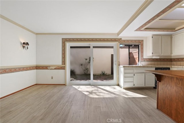 kitchen featuring crown molding, light countertops, baseboards, and light wood-style floors