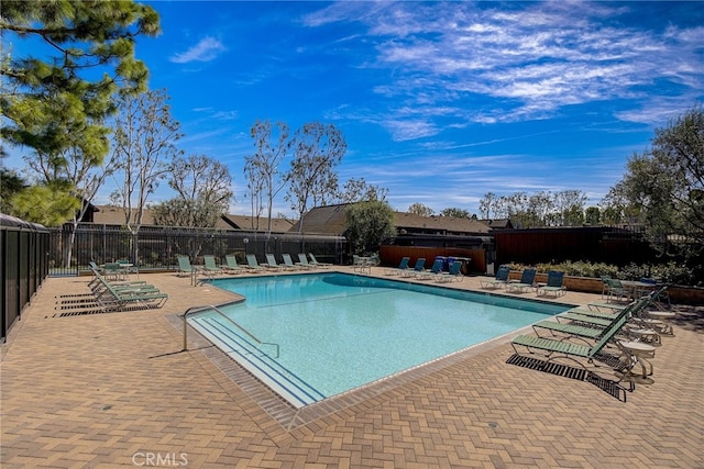 community pool with a patio area and fence