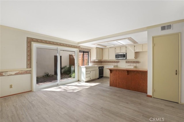 kitchen featuring light wood-type flooring, visible vents, stainless steel microwave, and light countertops