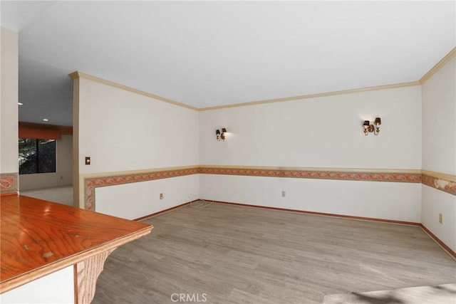 interior space featuring crown molding, light wood-style flooring, and baseboards