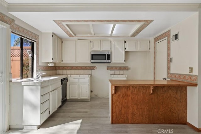 kitchen with visible vents, dishwasher, stainless steel microwave, a peninsula, and light wood-type flooring