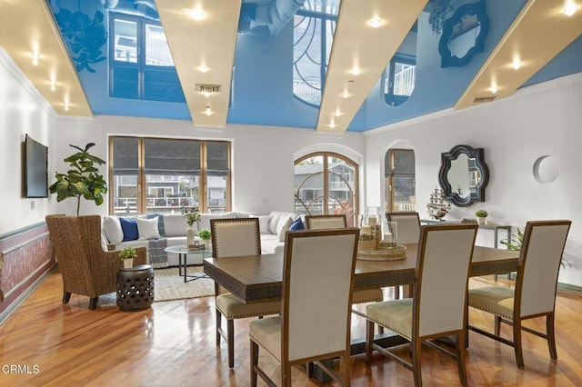 dining room with a wainscoted wall, crown molding, visible vents, and wood finished floors