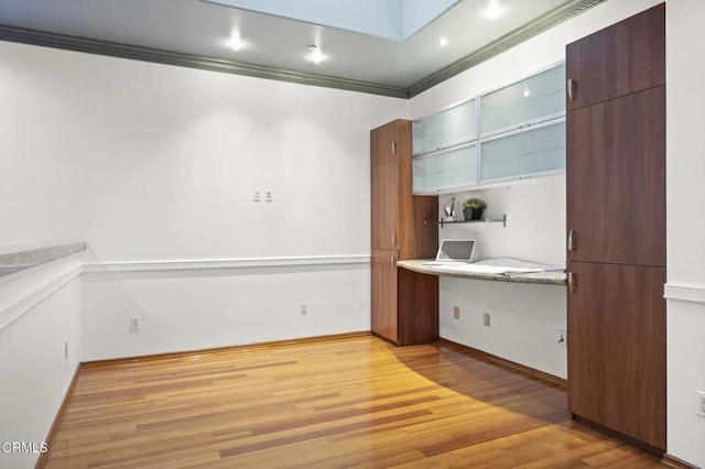 interior space with wood finished floors, light countertops, open shelves, built in desk, and crown molding