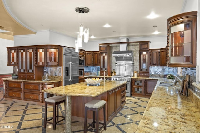 kitchen with a sink, a kitchen island with sink, high end appliances, and backsplash